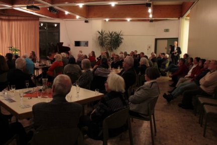 Blick in den Saal mit den Besuchern an den Tischen